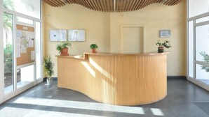 En receptionsdisk med träpanel, krukväxter och en anslagstavla med information.