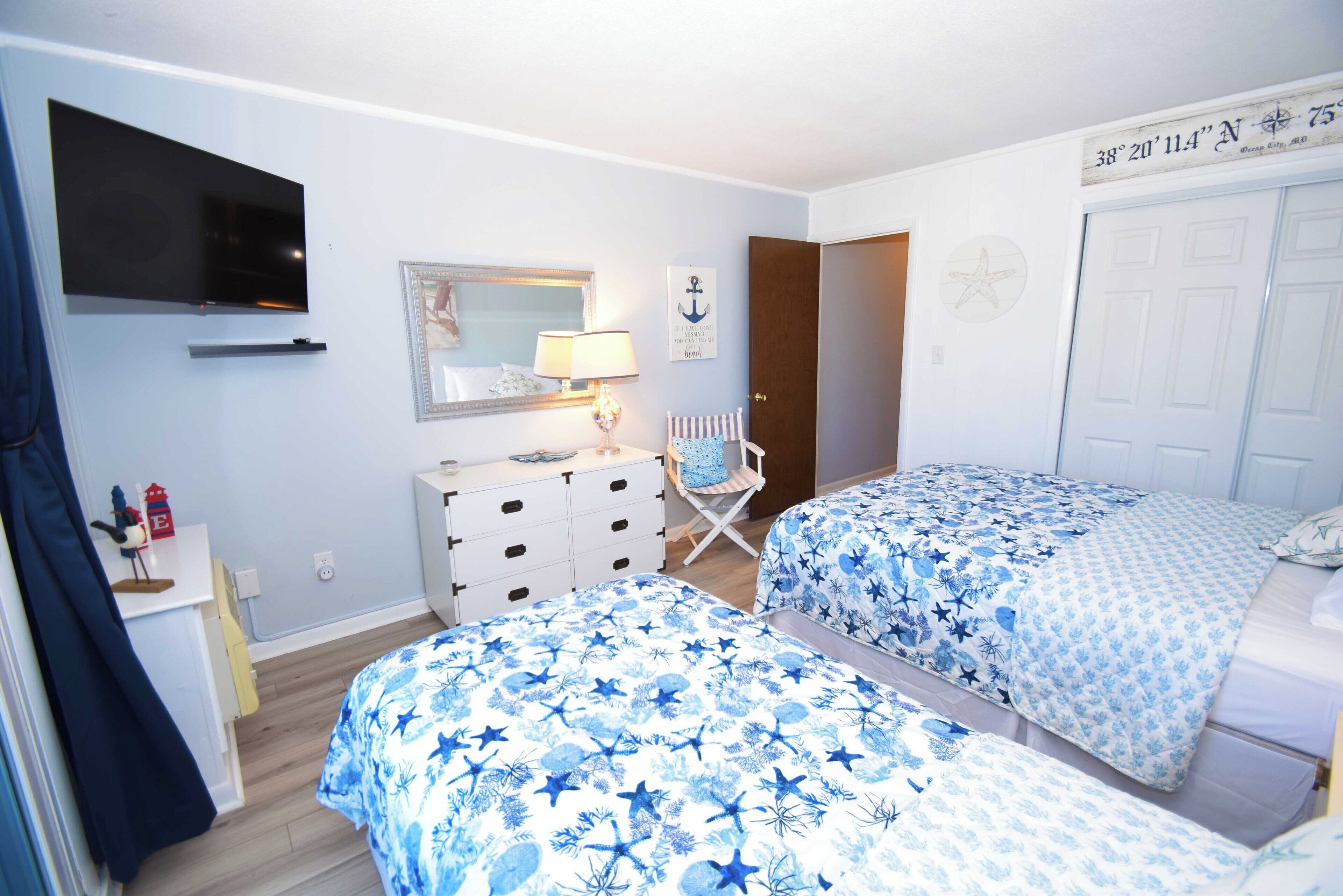 A bedroom with two beds, a TV, a dresser, and a chair.