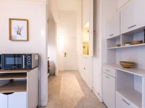 Una cocina moderna con armarios blancos, un microondas y un cuadro en la pared.