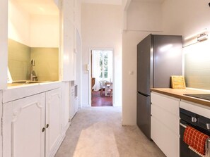 Una cocina con armarios blancos, un refrigerador de acero inoxidable y una encimera de madera.