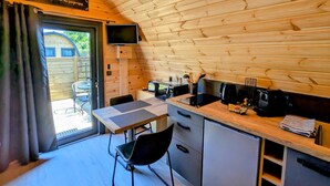 A compact kitchen with wooden walls, a dining table, and a TV mounted on the wall.