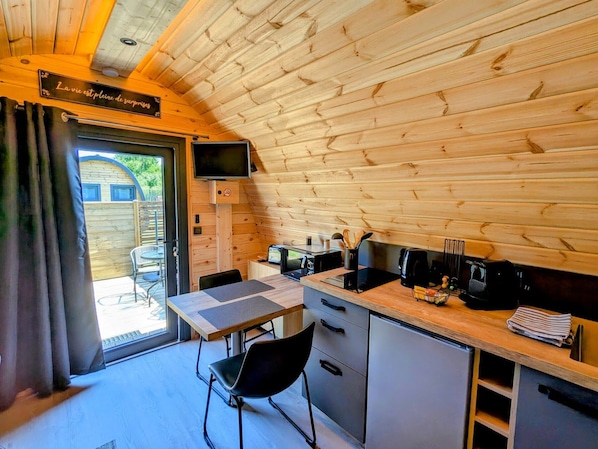Eine kleine Küche mit Holzwänden, einem Esstisch und einem an der Wand befestigten Fernseher.