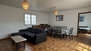 Un saló amb un sofà, taula de dinar, cadires i dos lustres.