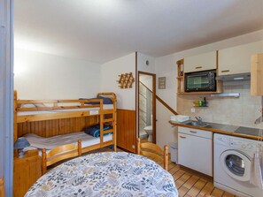 A compact room with a bunk bed, a small round table, a washing machine, a microwave, and a sink. - Cozy chalet, 4 pers., parking, near cable car (Cauterets)