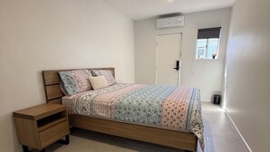 Une chambre à coucher comprenant un lit, une table de chevet, une fenêtre avec vue et un appareil de climatisation.