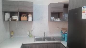 A kitchen with wooden cabinets, a double sink, and a refrigerator.