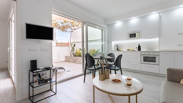 Un apartamento moderno con comedor, cocina y un balcón con plantas.
