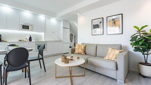 Un espacio habitable moderno con cocina, comedor y sofá con cojines decorativos.
