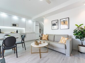 Ein moderner Wohnbereich mit Küche, Essbereich und einer Couch mit Zierkissen.