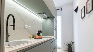 Una cocina moderna con salpicadero de mármol, un grifo negro y una encimera con tostadora y rodajas de tomate.