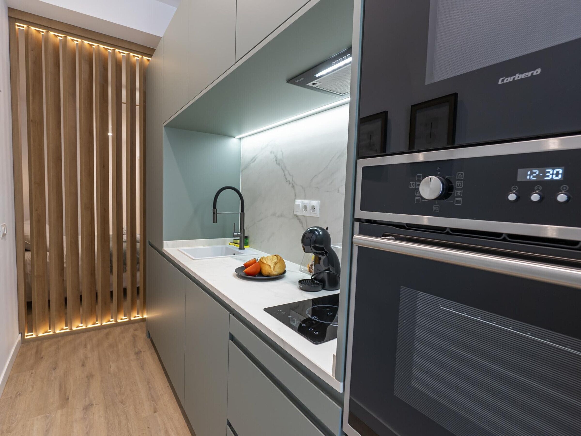 A modern kitchen with a built-in oven, a coffee machine, and a sink.