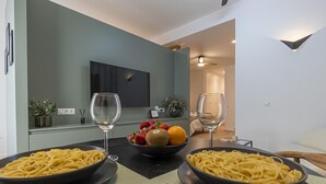 Un comedor moderno con dos platos de espagueti, un tazón de fruta y copas de vino sobre una mesa.