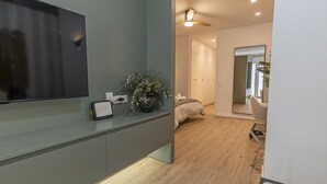Una sala de estar moderna con un televisor de pantalla plana, un altavoz pequeño y una planta en maceta.