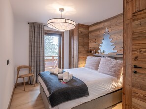 A bedroom with a bed, a wooden headboard, a nightstand, a chair, and a window with curtains. - Luxury apartment, Alpe d'Huez center (Huez)