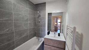 Un baño moderno con bañera, ducha y tocador con espejo.