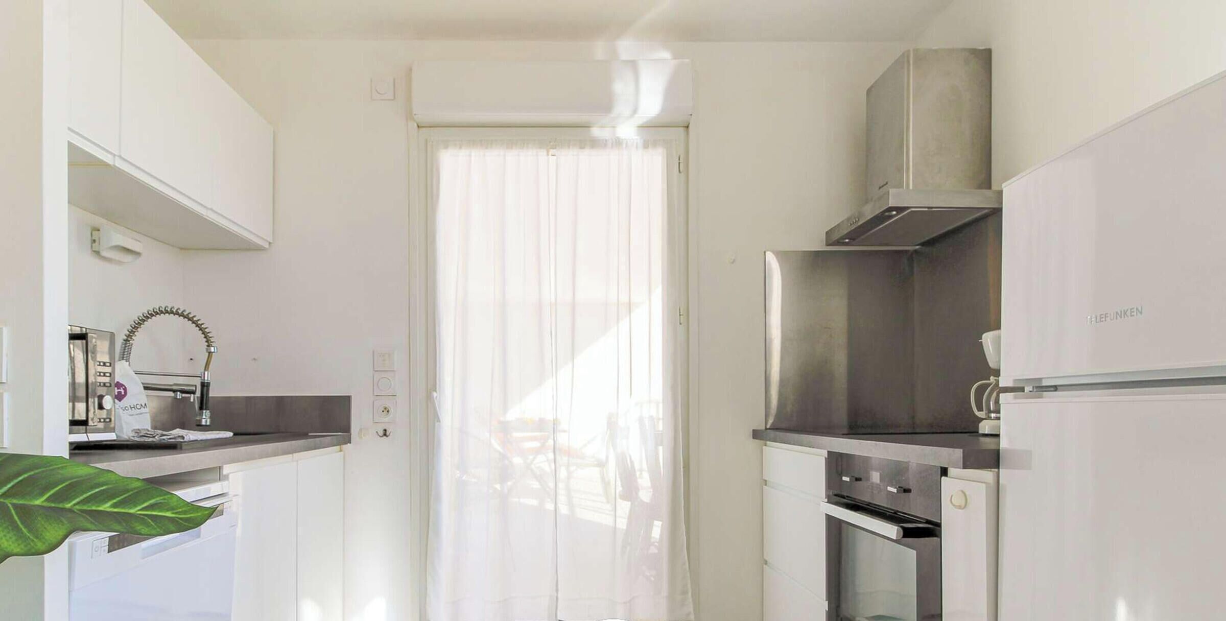 A compact kitchen with a built-in oven, a stainless steel range hood, and a white refrigerator.