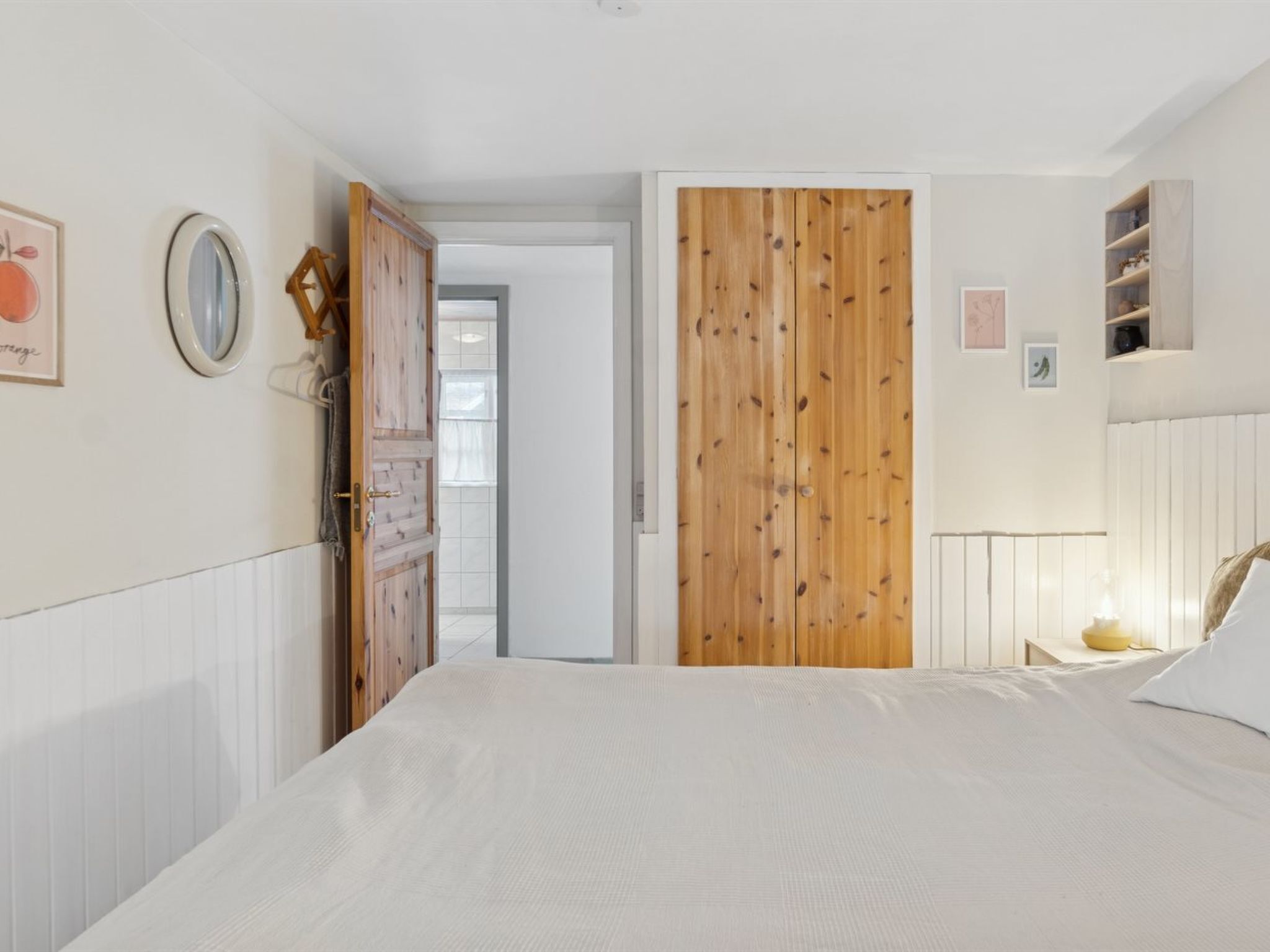 Ein Schlafzimmer mit Bett, Holzschrank und einer Tür zu einem anderen Raum.