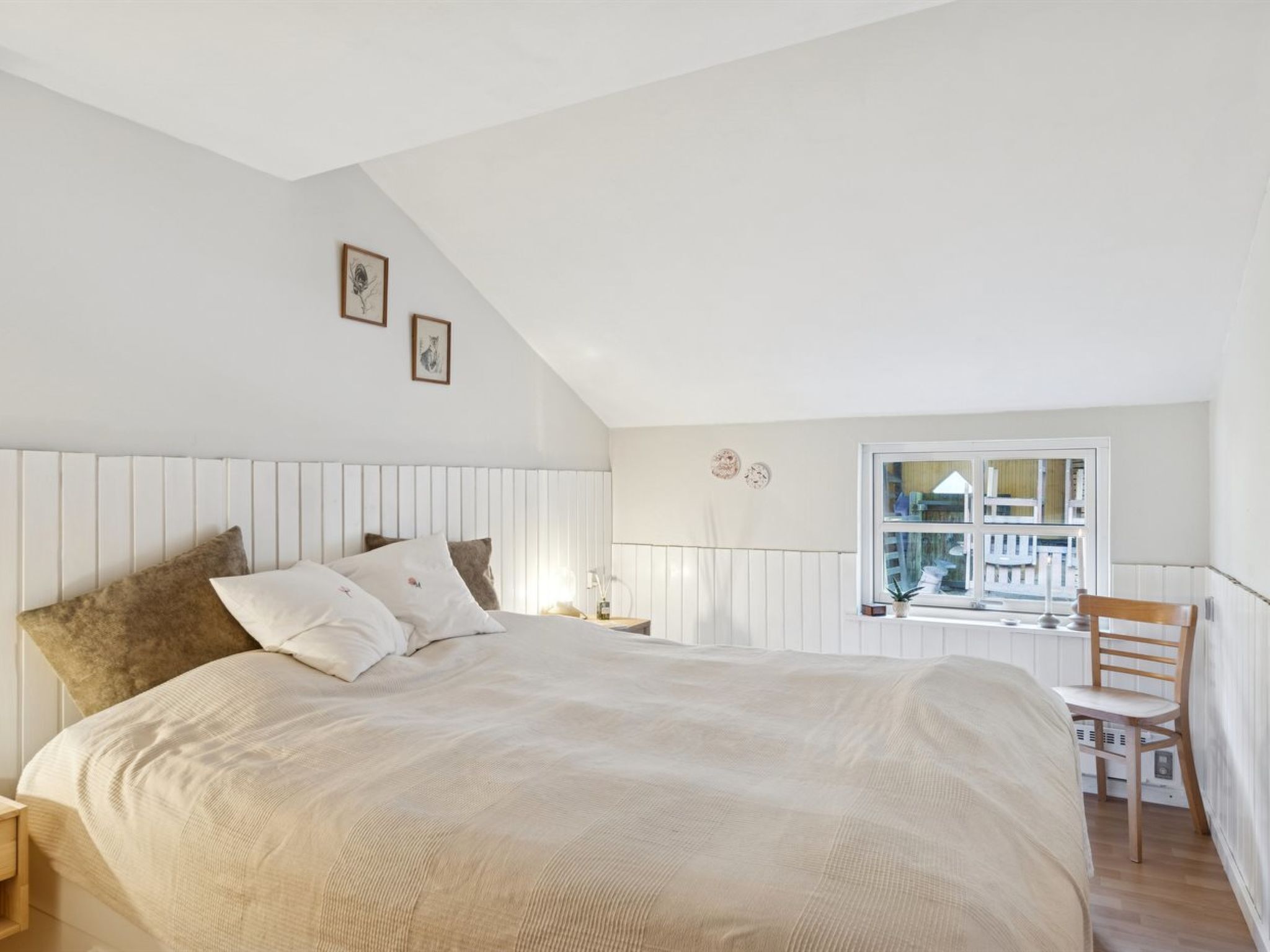 Une chambre avec un grand lit, une fenêtre donnant sur un beau paysage et un fauteuil.