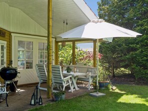 Un patio cubierto con mobiliario exterior, una parrilla y plantas en macetas.