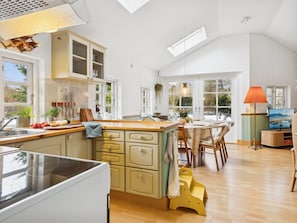 Una cocina con una isla grande, armarios de madera y una zona de comedor con mesa y sillas.