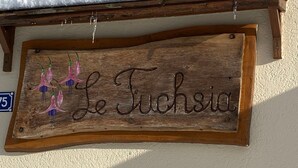 Une enseigne en bois portant l’inscription « Le Tuchsia » et ornée de piments décoratifs.