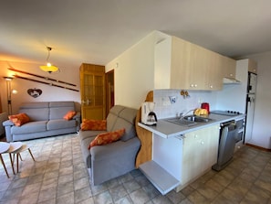 A compact living space with a kitchenette, a sofa, a dining table, and a small kitchen island. - Comfortable apartment with parking near Châtel center (Châtel)