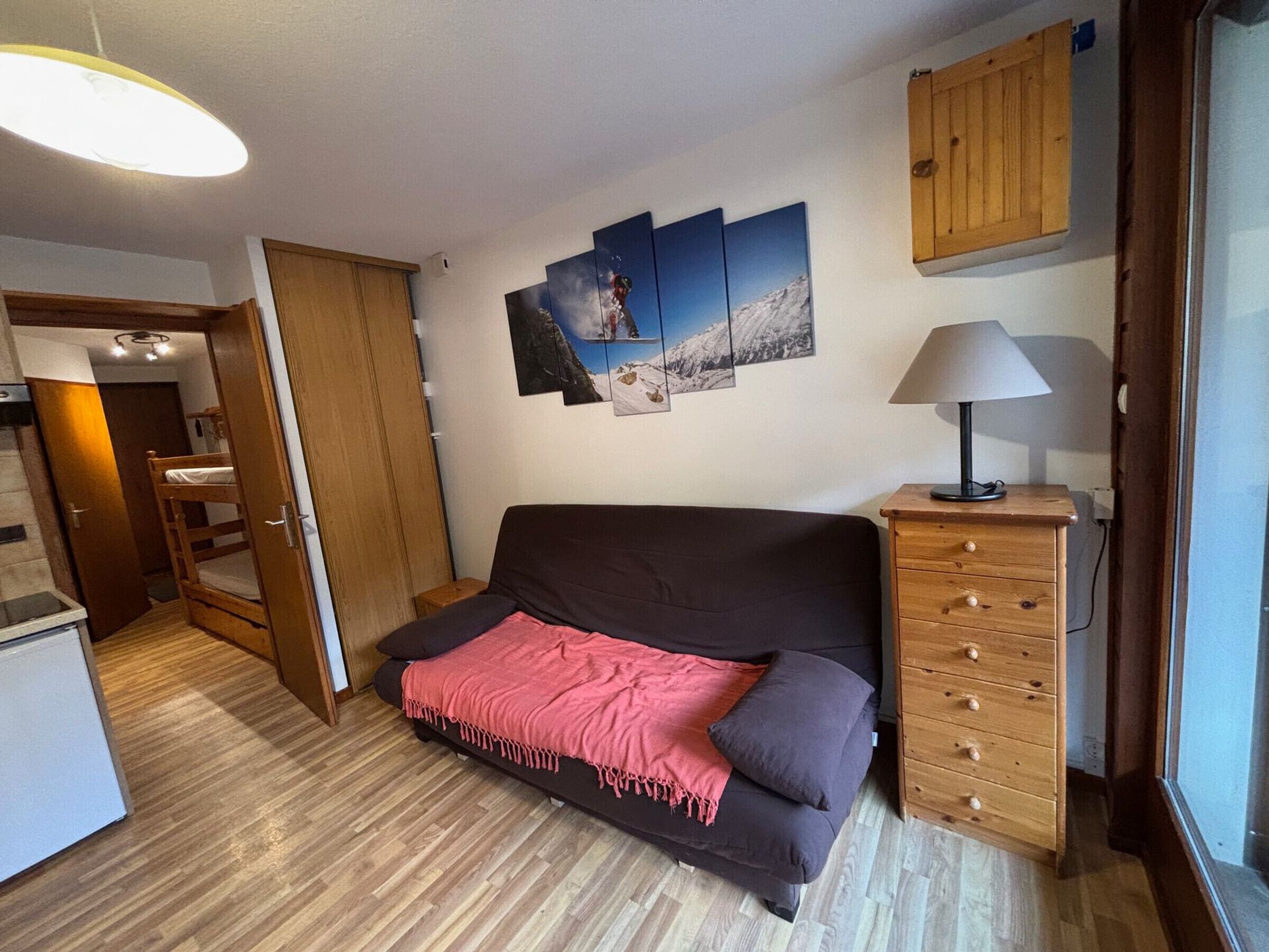 Un espace de vie compact comprenant un canapé, un meuble en bois et une lampe fixée au mur.