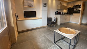 A modern kitchen with a built-in oven, microwave, and a dining area with a round table. - Renovated studio for 4 with balcony in Grand-Bornand (Le Grand-Bornand)