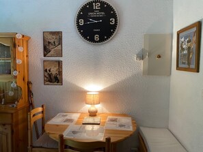 A room with a round wooden table, a wall clock, and two framed pictures. - Family apartment near lifts, parking, south terrace (Châtel)