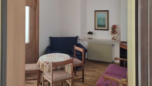 A corner room with a wooden ceiling, a radiator, a framed picture, and a small table with a chair. - Appartment le Gemme Dolomites escape (Dosoledo)