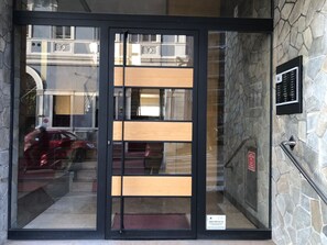 A modern building entrance with a glass door, stone wall, and a metal staircase. - Near Trieste city center - Apartment for couples, families and business trips (Trieste)