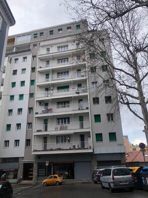 A multi-story residential building with balconies, a ground-level entrance, and parked cars. - Near the center of Trieste - Apartment for couples, families, and business travelers (Trieste)