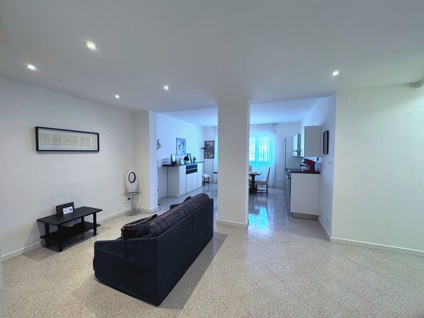 A modern living room with a sofa, a small table, and a framed picture on the wall. - Near the center of Trieste - Apartment for couples, families, and business travelers (Trieste)