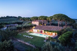 Eine Villa mit Swimmingpool, umgeben von üppiger Vegetation und Bäumen.