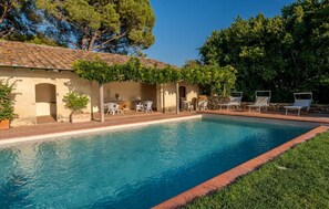 A swimming pool with a tiled deck, surrounded by lounge chairs and a small patio area with tables and chairs. - Tenuta San Crescenzio (Toscana)