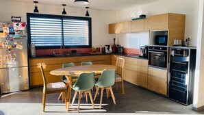 Eine moderne Küche mit Essbereich, ausgestattet mit einem großen Fenster, Holzschränken und Edelstahlgeräten.