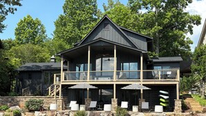 Ein zweistöckiges Haus mit Balkon, Steintreppe und Außenbereich mit Sitzgelegenheiten.
