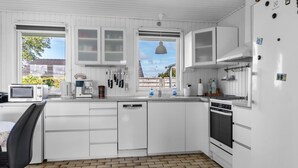Una cocina moderna con armarios blancos, lavavajillas integrado, estufa y microondas.