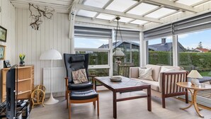 Una habitación amplia con un gran ventanal, un sofá cómodo, una mesa de madera y una silla.