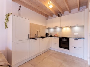 A modern kitchen with white cabinets, a black countertop, and a built-in oven. - Modern Holiday Home in Vrouwenpolder (Koudekerke)