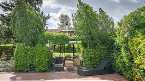 Una piscina con sillas de descanso y una pérgola, rodeada de exuberante vegetación.