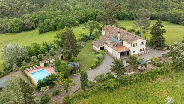 Una casa con piscina, rodeada de exuberante vegetación y colinas.