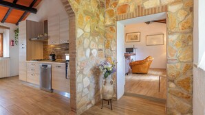 Una cocina moderna con pared de piedra, armarios de madera y horno empotrado.