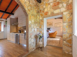 Una cocina moderna con pared de piedra, armarios de madera y horno empotrado.
