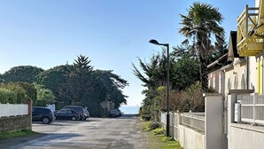 A paved road leading to a building with a white fence and parked cars. - Sanoubott by Interhome (La Bernerie-en Retz)