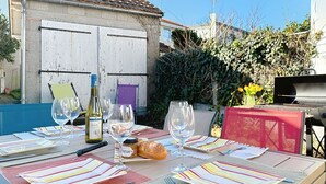 A table set outdoors with wine glasses, a bottle, and a loaf of bread. - Sanoubott by Interhome (La Bernerie-en Retz)