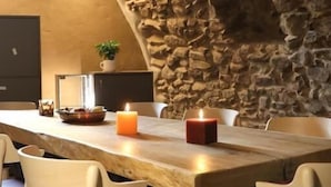 Un comedor rústico con pared de piedra, mesa y sillas de madera.