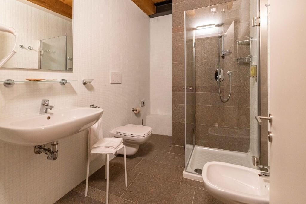 Ein modernes Badezimmer mit einem großen Waschbecken, einer Toilette und einer begehbaren Dusche.