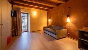 Una habitación acogedora con vigas de madera, un sofá y dos lámparas de pared.