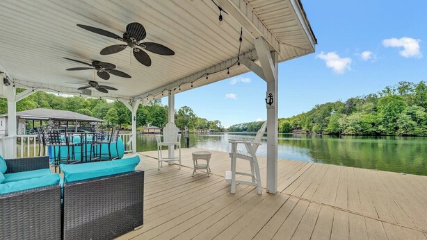 Una terraza cubierta al aire libre con asientos, una piscina y vistas a un lago.